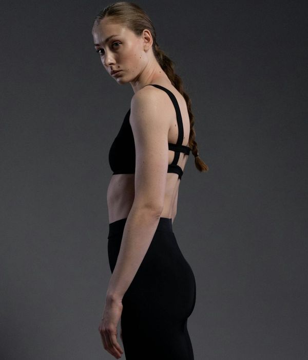 Woman in a calm, focused yoga pose against a dark background.